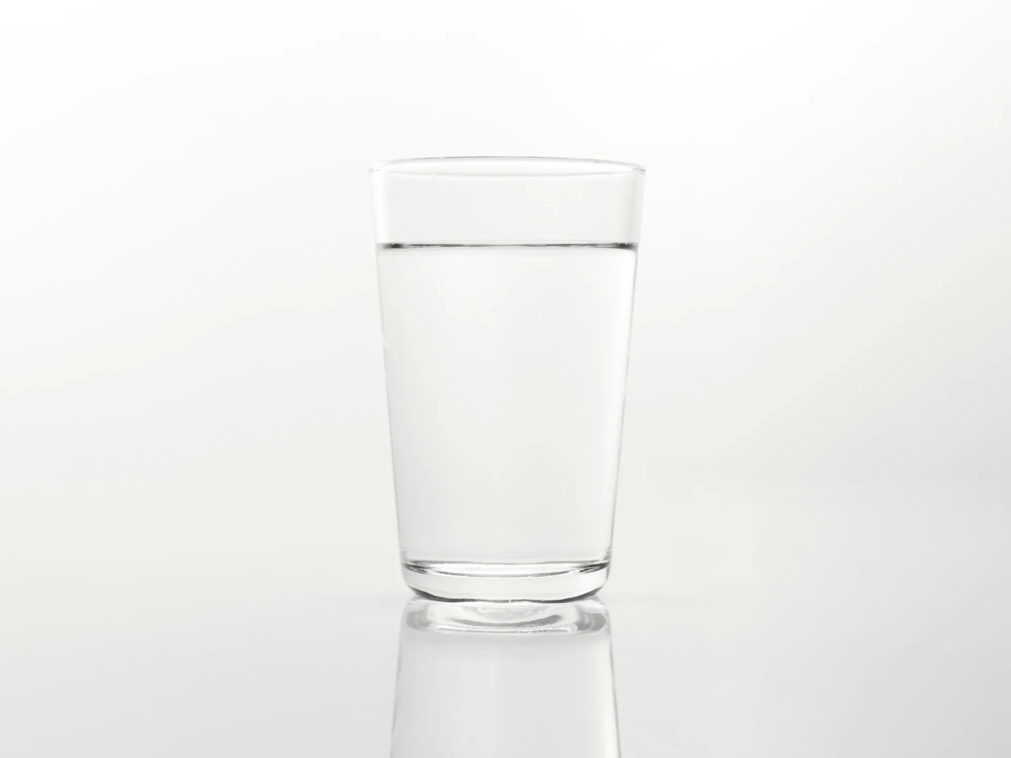 Newport Beach Water Filtration Resources Glass of clear drinking water on a reflective white surface