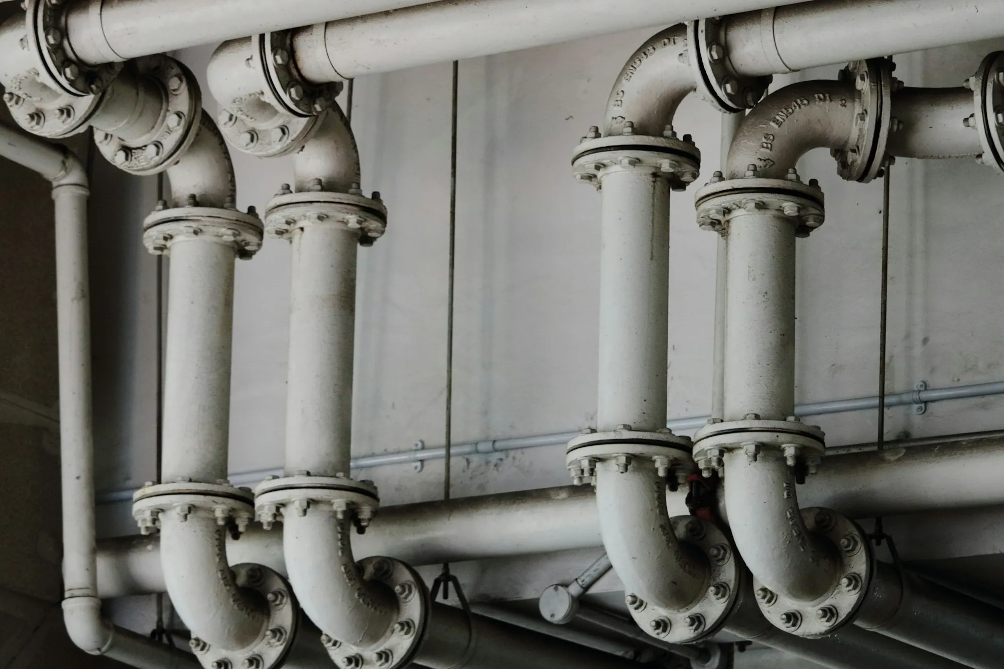 Rows of white water pipes along a wall